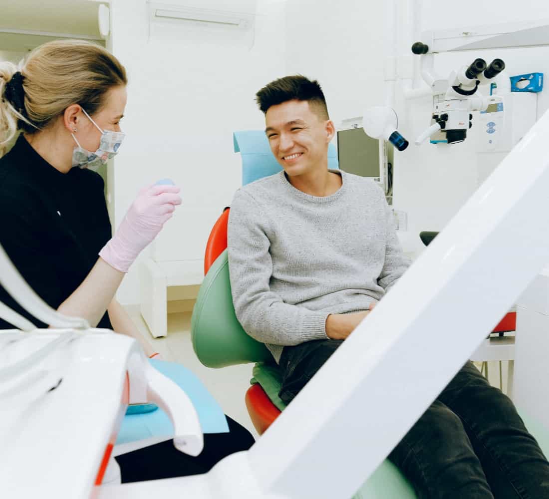 Patient happy and smiling in a dentist's chair.